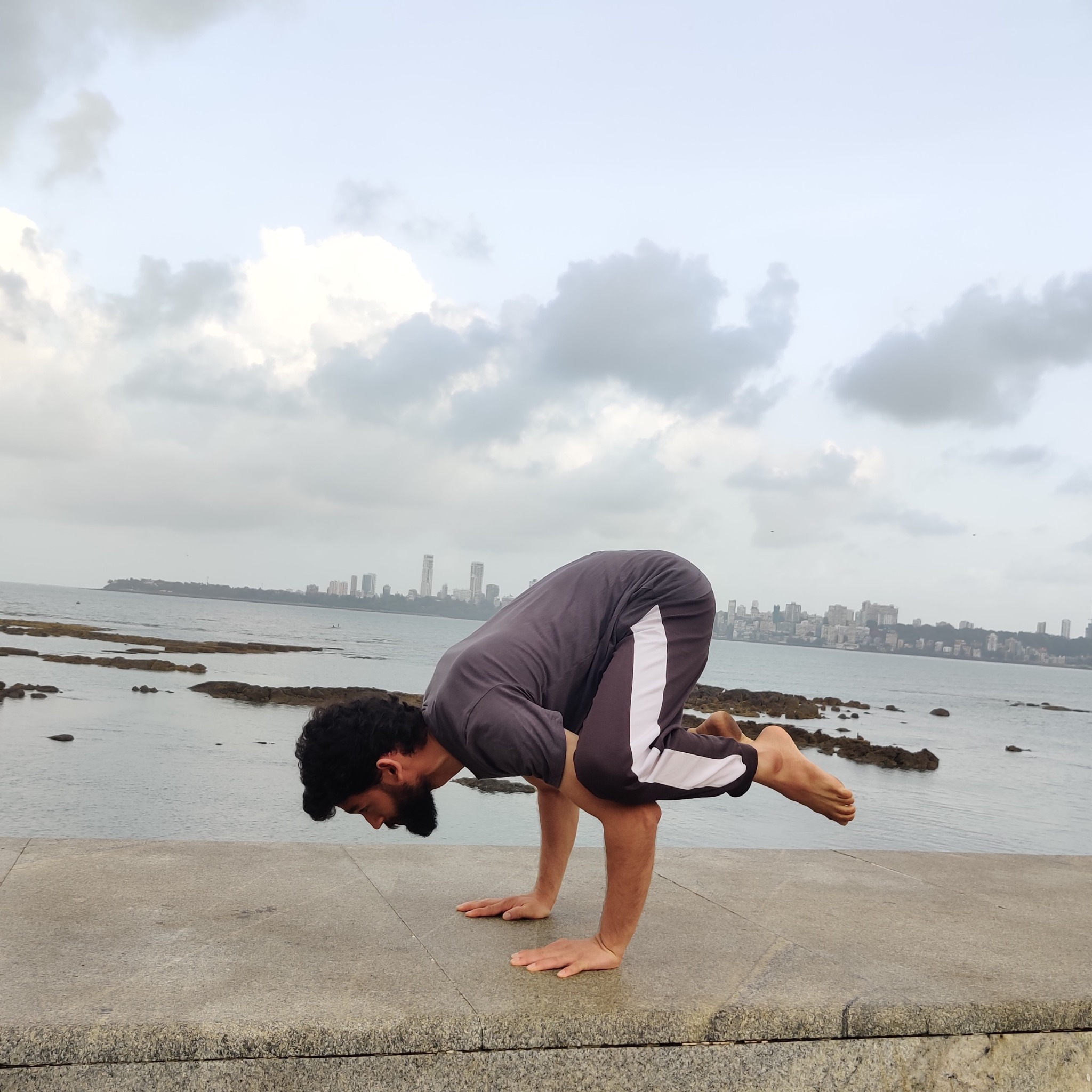 Abhinav Gupta practising an arm-balance posture beside the sea